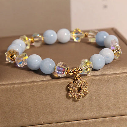 Women's aquamarine crystal bracelet with four-leaf clover charm and pearl details on wrist
