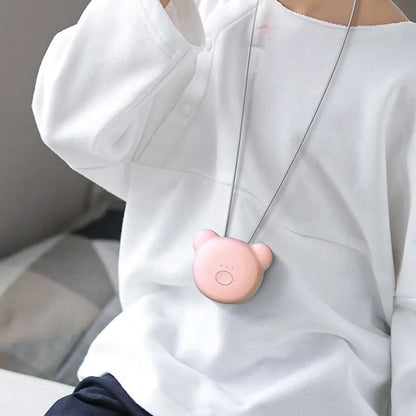 A person wearing a small, blue USB-rechargeable air purifier on a necklace, showing its compact size.
