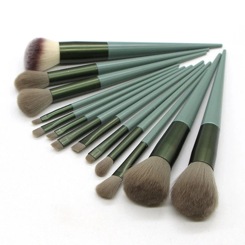13 green makeup brushes with plastic handles and aluminium ferrules arranged with storage bag
