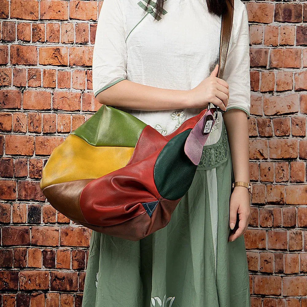 Brown cowhide leather travel bag with crossbody strap, showing stitching detail.