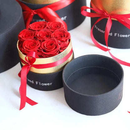 Luxury gift box containing an arrangement of preserved red eternal roses on a dark background.