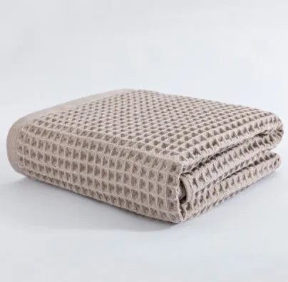 Large light-coloured cotton bath towel with a textured surface, measuring 140 by 70 centimetres.