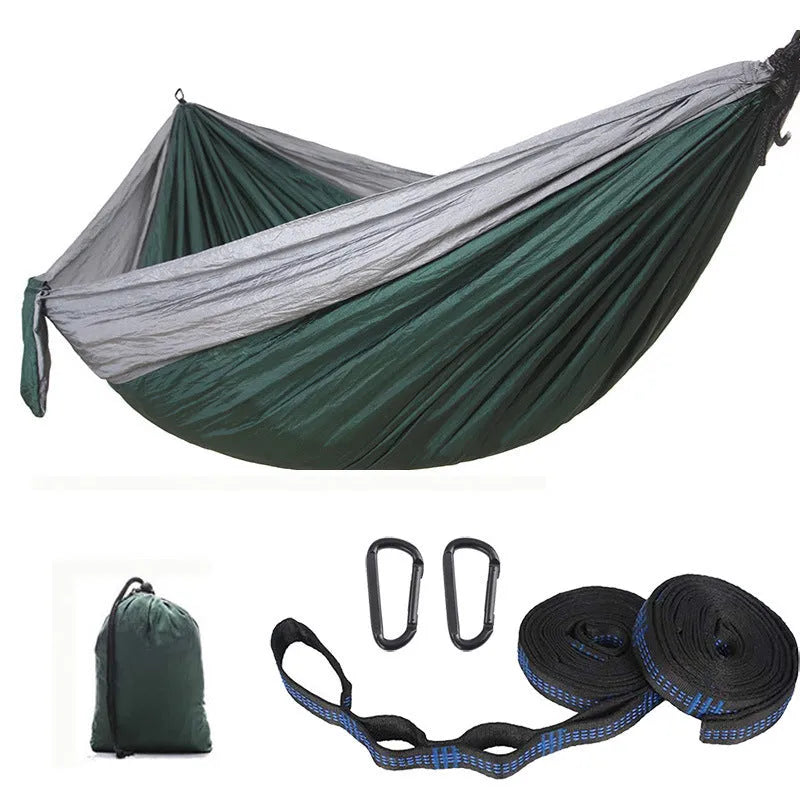 Parachute cloth double camping hammock in chosen colour, with black buckles and round ropes on a tree.
