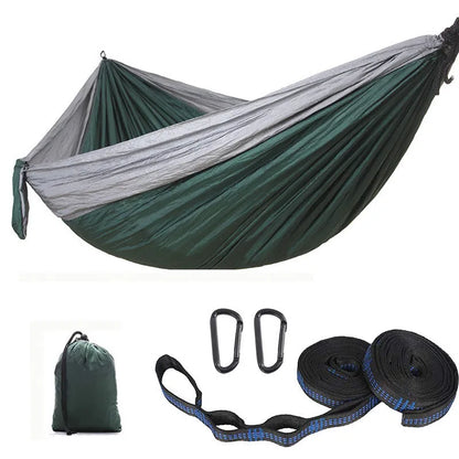 Parachute cloth double camping hammock in chosen colour, with black buckles and round ropes on a tree.
