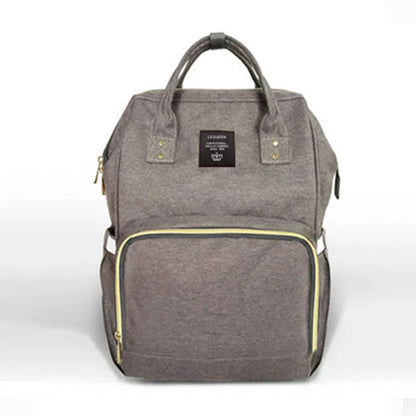 Stylish maternity diaper bag in various colors, featuring a paper bag design, separate bottle compartment, and discreet breastfeeding button.