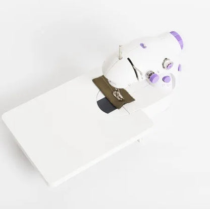Compact white mini electric household sewing machine with work light and thread cutter.