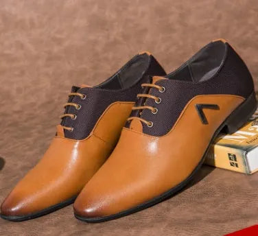 Men's black Oxford dress shoes with a rubber sole on a wooden floor.
