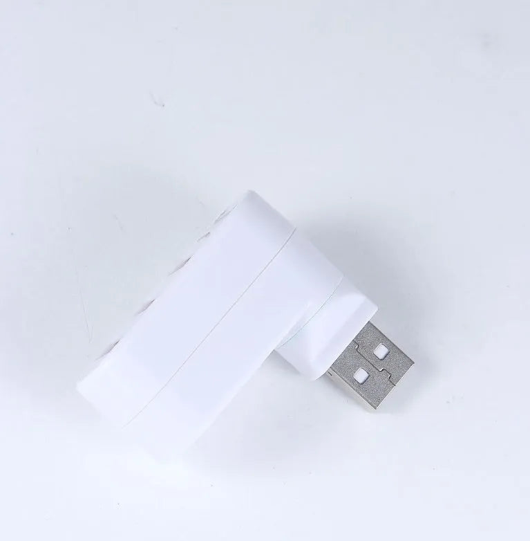 Black and white USB 2.0 hub splitter with spin colour casing on a desk next to a laptop.