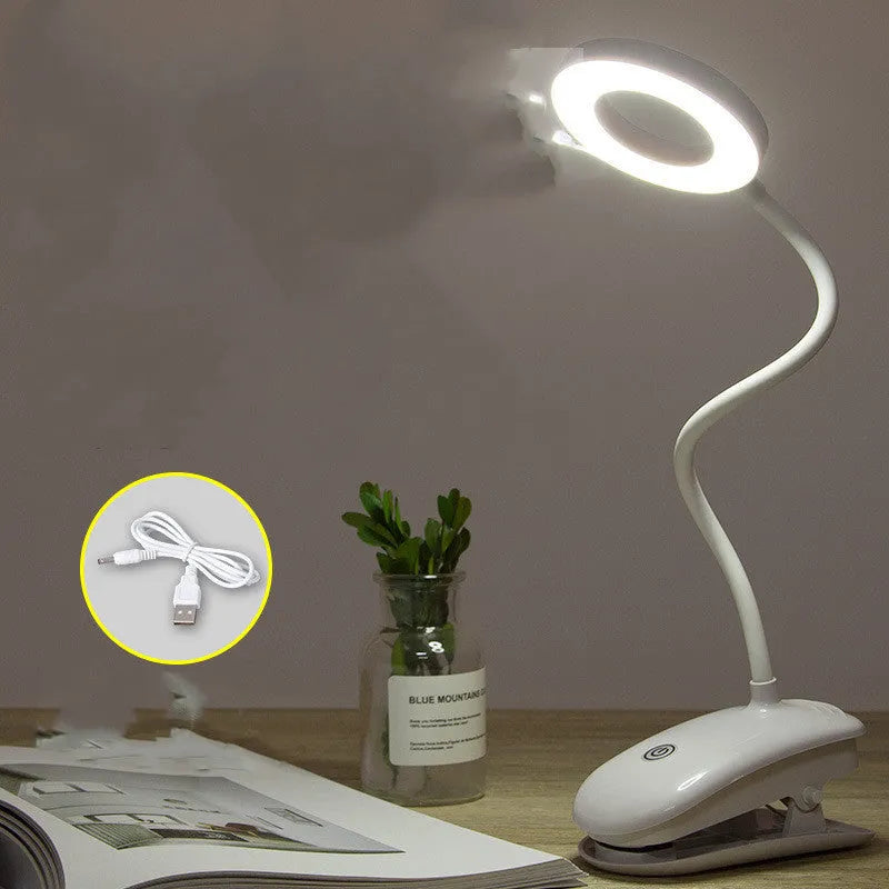 A modern white clip-on rechargeable desk lamp with a touch-sensitive switch and a plastic shade.