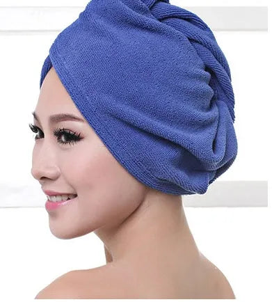 A woman wearing a sky blue microfiber hair dryer cap, with wet hair tucked inside, showing the towel's wrap-around design.