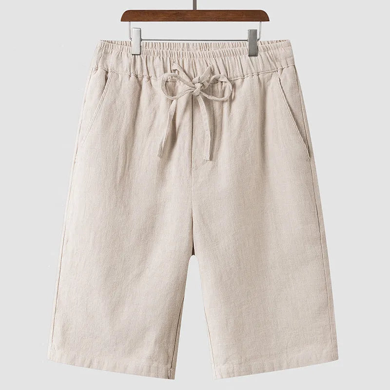 Men's beige linen casual shorts with a loose fit and elastic waistband on a neutral background.