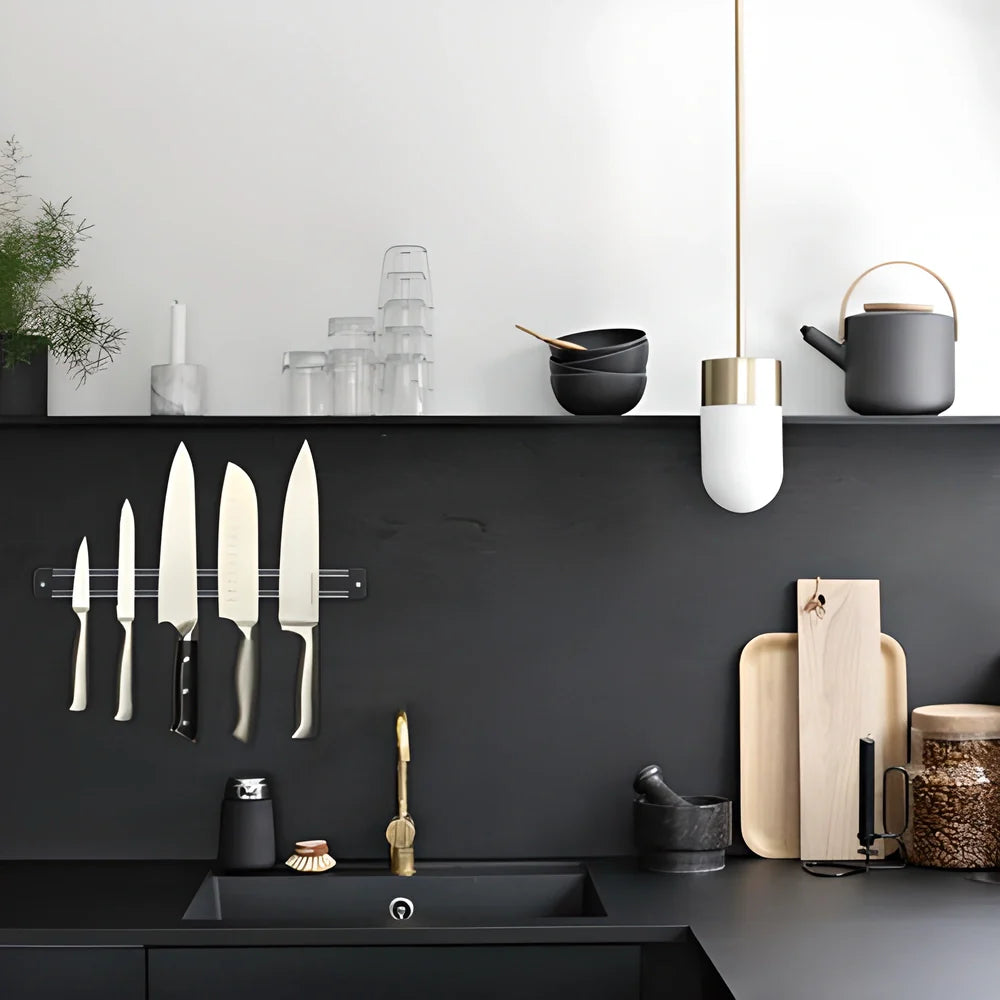 A sleek, stainless steel magnetic wall-mounted knife and tool holder, neatly displaying a variety of kitchen knives and garage implements.