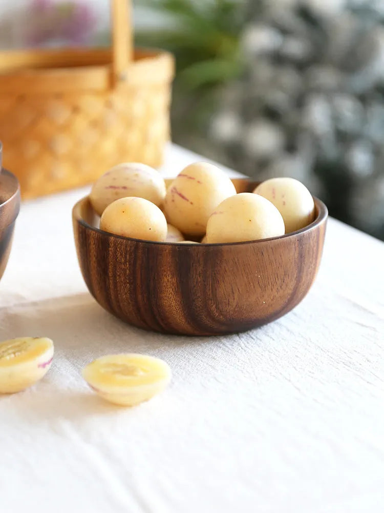 Set of five brown wooden bowls in different sizes on a wooden table, showing natural grain.