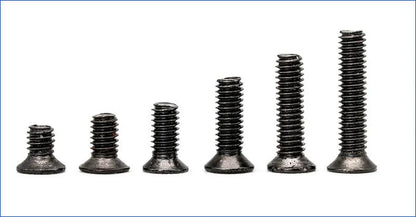 Black laptop machine screws with countersunk cross heads, shown in loose pile and close-up