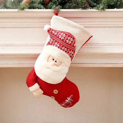 Large red and white knitted Christmas stocking with Santa Claus design hanging on a fireplace.