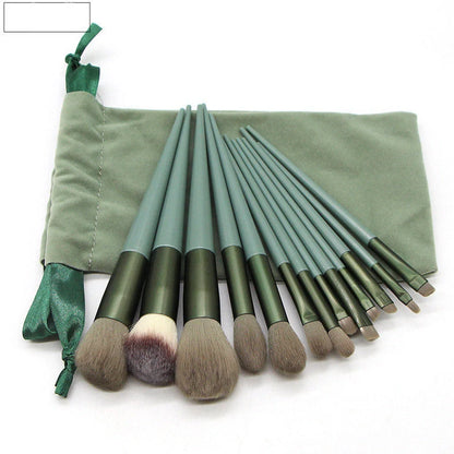 13 green makeup brushes with plastic handles and aluminium ferrules arranged with storage bag