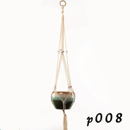 Handwoven natural cotton rope plant hanger cradling a green potted succulent on a wooden table.