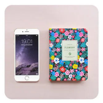 Green floral notepad with fabric imitation leather cover lying open on a table.