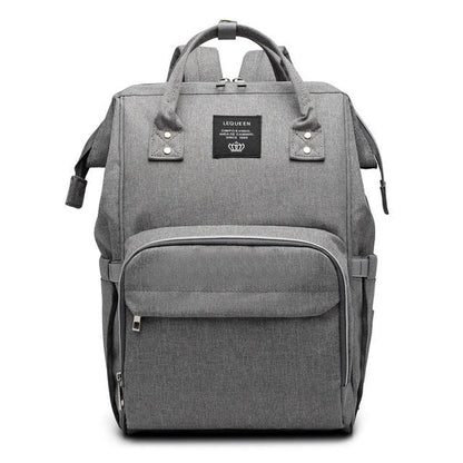 Stylish maternity diaper bag in various colors, featuring a paper bag design, separate bottle compartment, and discreet breastfeeding button.