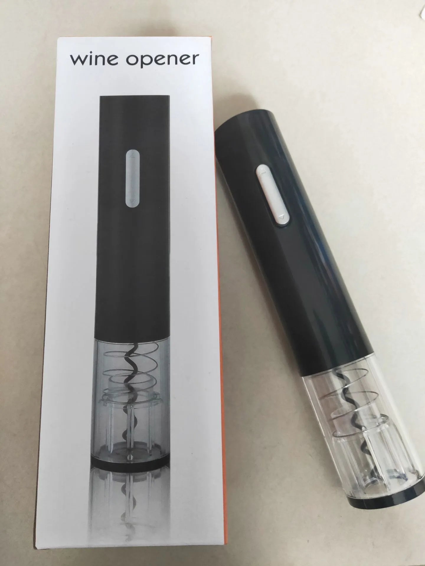 Black automatic electric wine opener with foil cutter showing battery compartment and cork removal mechanism