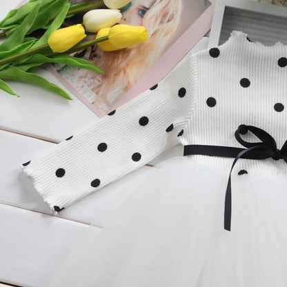 Baby girl wearing a long sleeve black tutu dress with lace detail for a birthday party.