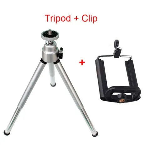 Black mini camera tripod with extended legs and a separate U-shaped universal phone clip on a table.
