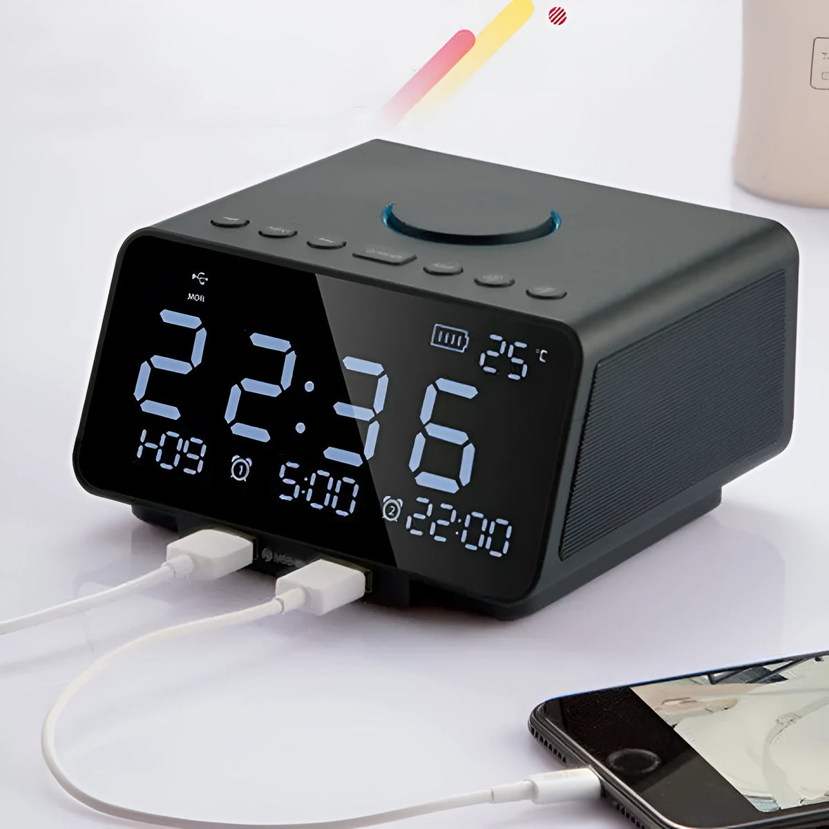 Black and white wireless alarm clock Bluetooth speaker with remote control on a table.