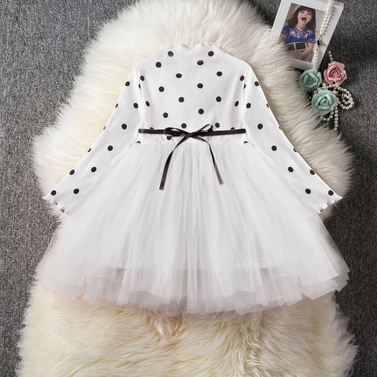 Baby girl wearing a long sleeve black tutu dress with lace detail for a birthday party.