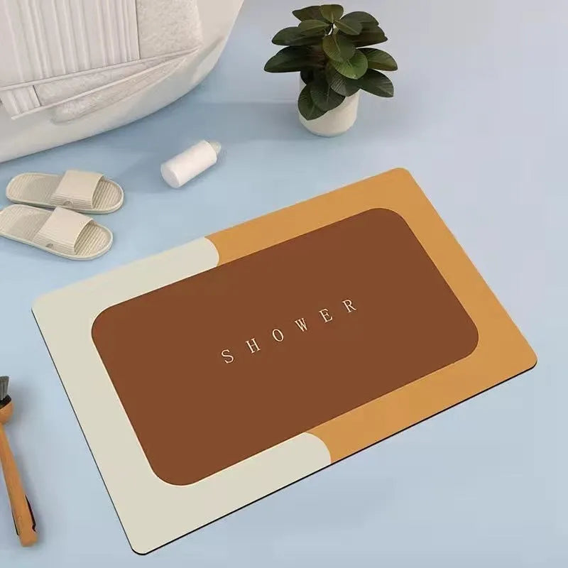 Oval grey bath mat with non-slip rubber bottom on a tiled floor, showing absorbent fabric surface