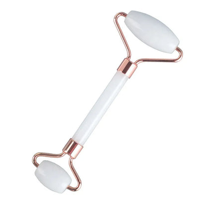 White jade facial roller with double-headed claw design and matching scraping board on dark surface