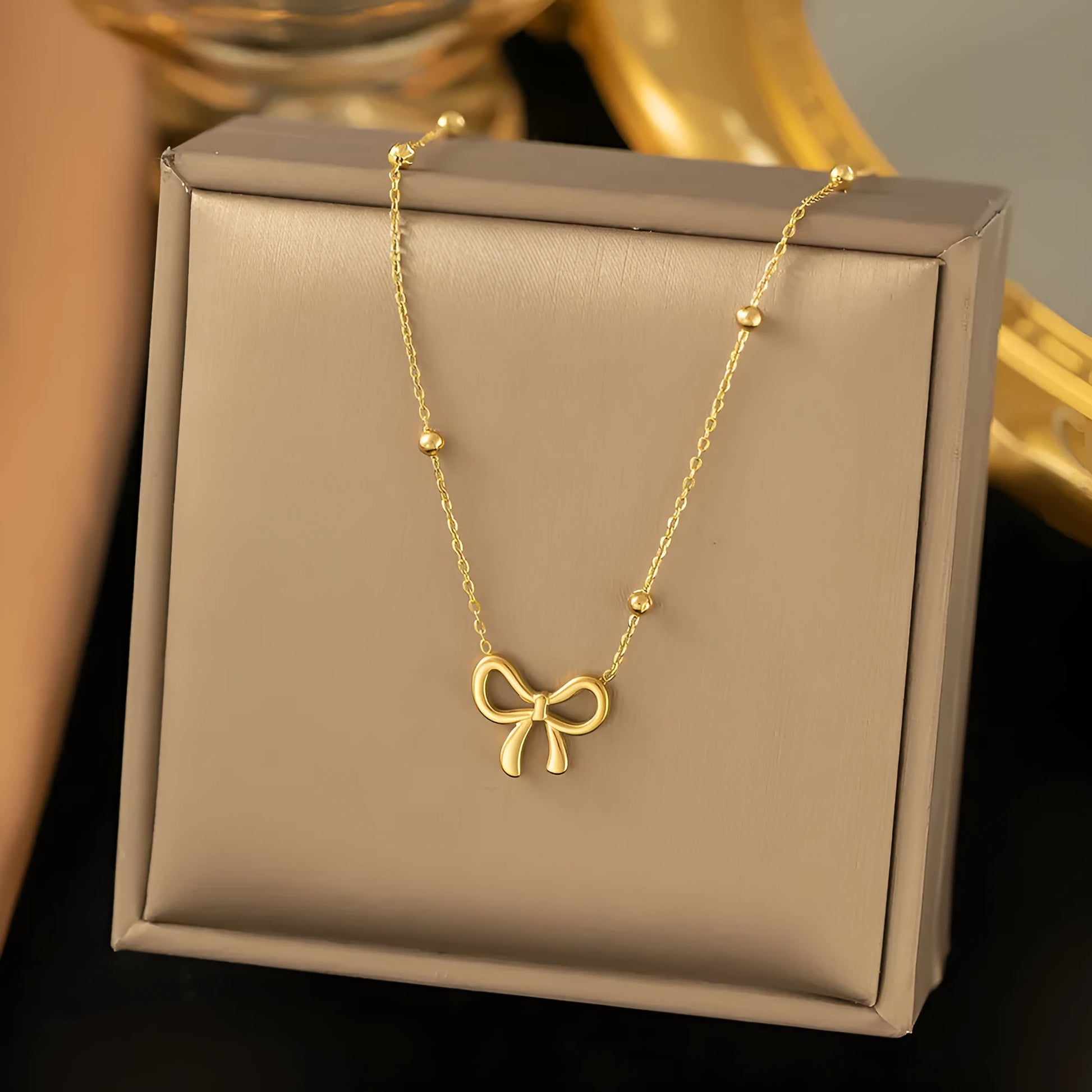 Gold adjustable bow necklace on a cross-link chain, showing the detailed pendant and clasp.