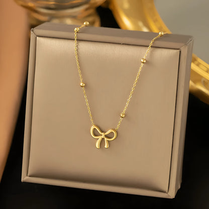 Gold adjustable bow necklace on a cross-link chain, showing the detailed pendant and clasp.