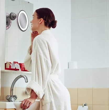White 10x magnifying LED makeup mirror with flexible gooseneck and suction cup base on a table.