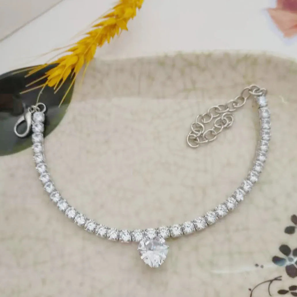 A heart-shaped rhinestone pendant on a gold plated adjustable collar for a small dog, showing the buckle and extension chain.