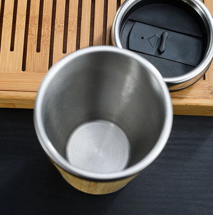 Natural bamboo fibre and stainless steel reusable travel coffee cup with black leak-proof lid on a table