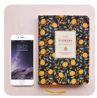 Green floral notepad with fabric imitation leather cover lying open on a table.