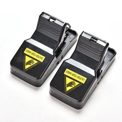 Six black plastic snapping mousetraps laid out on a surface, showing their size and smooth construction.