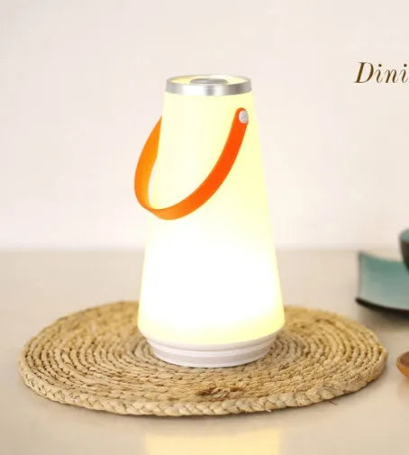 White rechargeable LED lantern with USB cable on a bedside table.