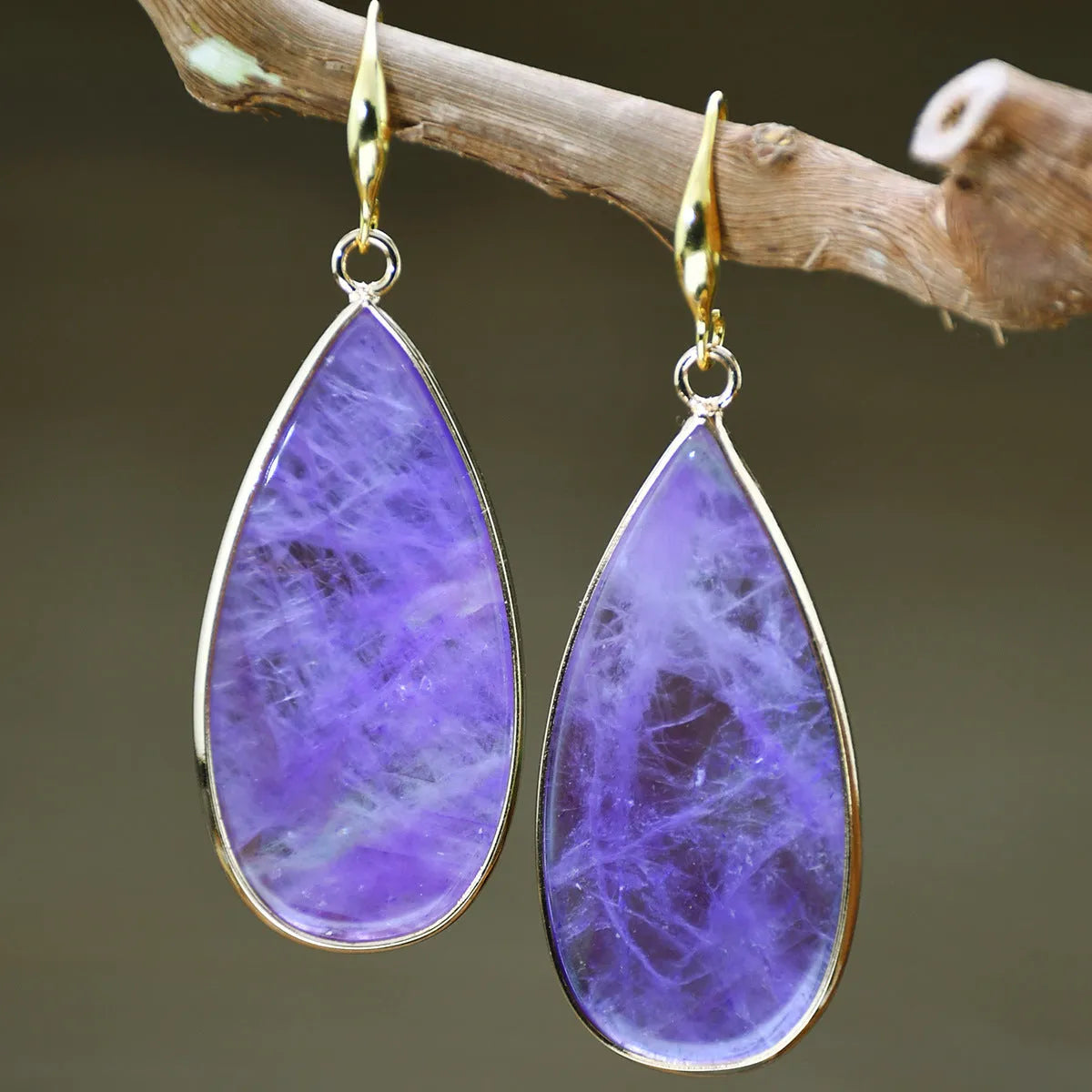 Handmade vintage long water drop earrings with tigereye stone and sterling silver hooks on a textured background.