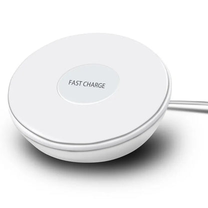 White wireless charging pad with digital clock display and three control buttons on a bedside table.