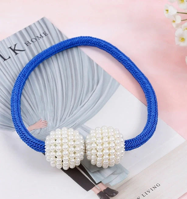 Magnetic curtain tiebacks with white pearl beads and fabric loops holding gathered curtain