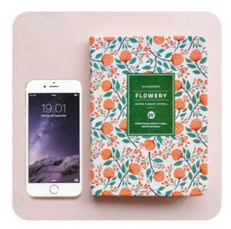Green floral notepad with fabric imitation leather cover lying open on a table.