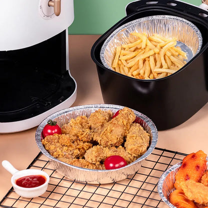 Round disposable aluminium foil liners for air fryers in four different sizes on a kitchen counter.