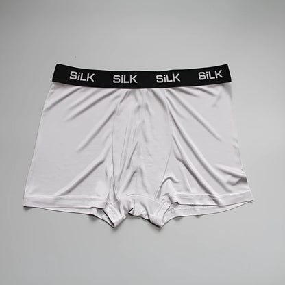 Man wearing loose-fit mid-waist shorts in navy blue silk fabric.