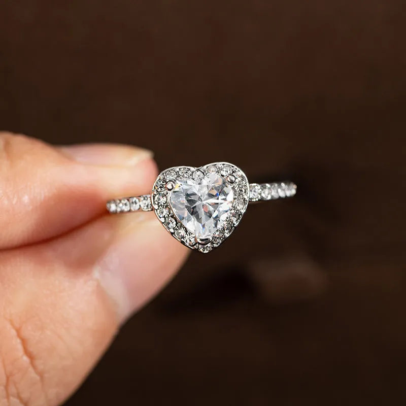Women's heart-shaped crystal ring in rose gold or silver tone on white copper.