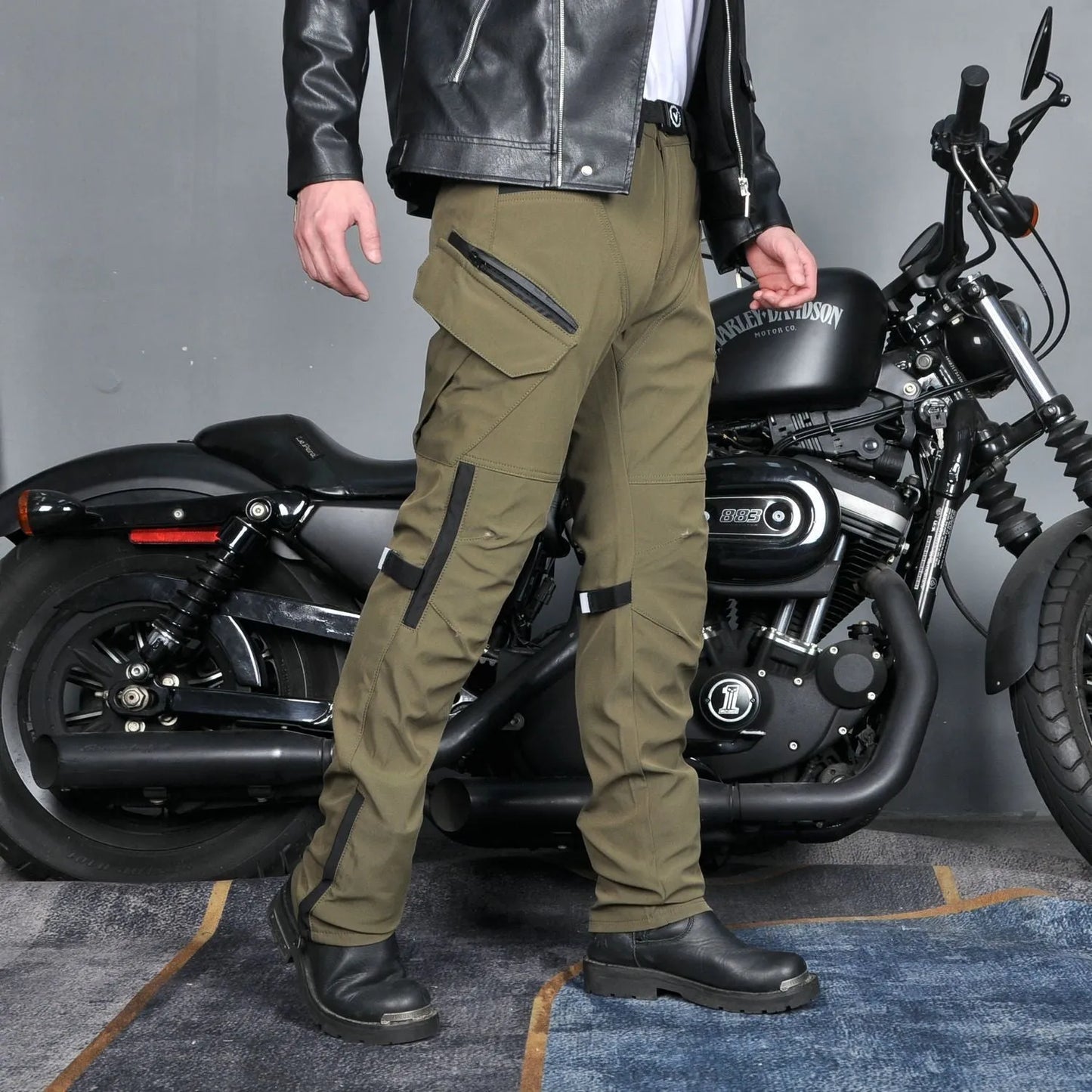Motorcycle rider wearing green waterproof trousers with removable protective armour on knees and hips.