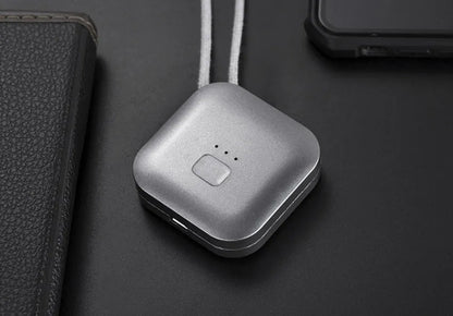 Small pink wearable air purifier pendant on a necklace, showing USB charging port and single button.