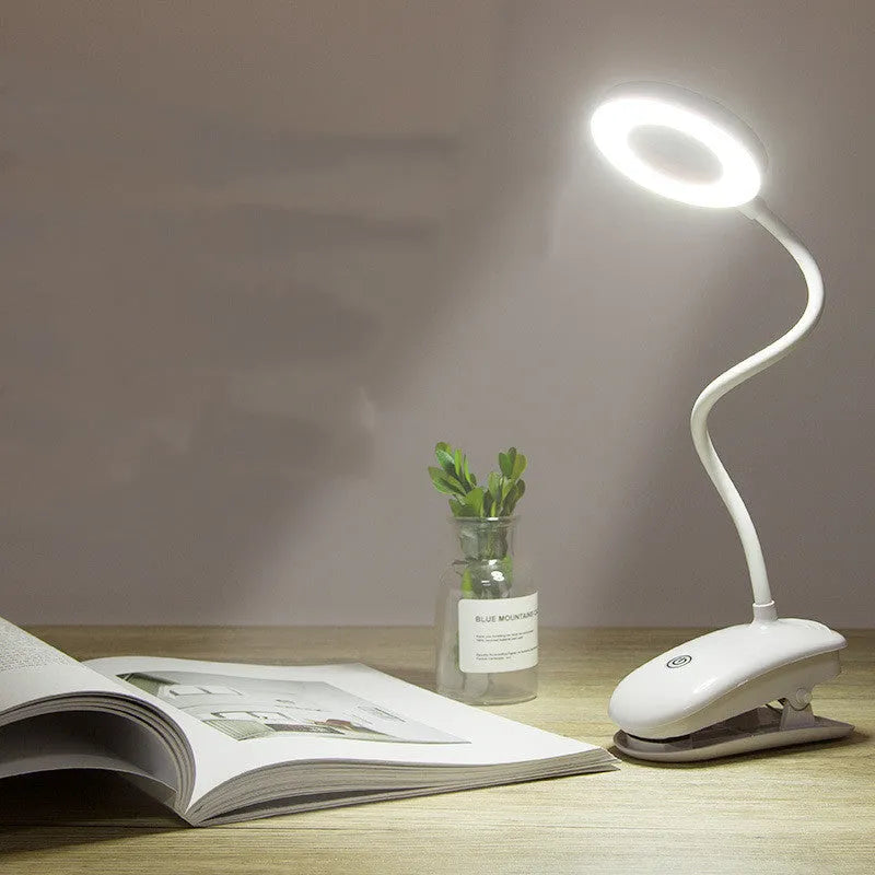 A modern white clip-on rechargeable desk lamp with a touch-sensitive switch and a plastic shade.