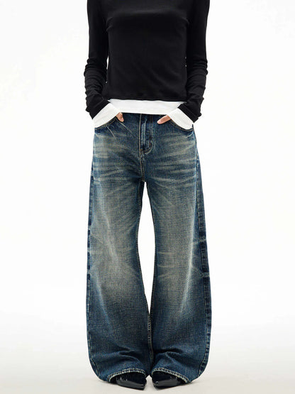 Men's wide leg mid waist jeans in dark blue denim with straight loose cut and distressed cat beard detail