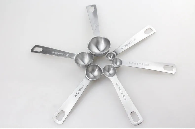 Set of six stainless steel measuring spoons connected by a silver D-ring, showing engraved measurement markings